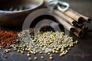 Scattered sesame seeds and herbs with cinnamon on wooden tabletop