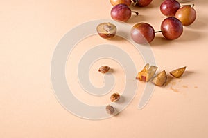 Scattered sliced half ripe sweet plum fruits with water drops near to plums slices and seed on cream colored background