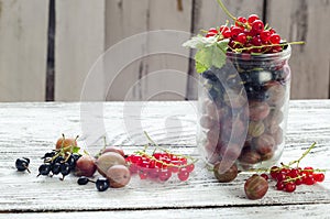 Scattered small organic fruit, red, black currant and gooseberries on a wooden table