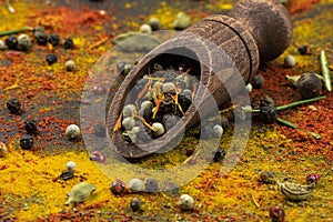 Scattered spices, wooden spoon with a mixture of peppers as a background