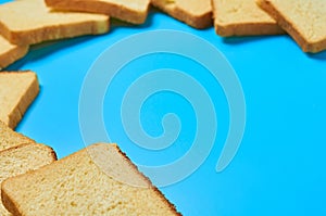 Scattered square pieces of yellow vanilla bread for toast lies on blue table on kitchen