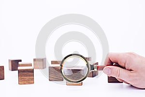 Scattered wooden cubes on a white background. Blocks. Magnifying glass. Research and meticulousness