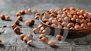 Scattered on a wooden table and in a clay bowl hazelnuts. Vegetarian cuisine