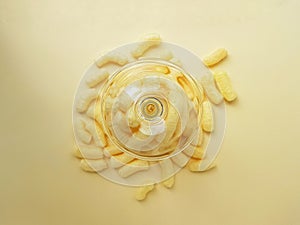 Scattered yellow sweet corn sticks from a glass on a yellow background. Children`s sweets.