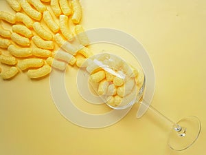 Scattered yellow sweet corn sticks from a glass on a yellow background. Children`s sweets.