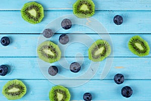 A scattering of blueberries and kiwis on a wooden blue background top view