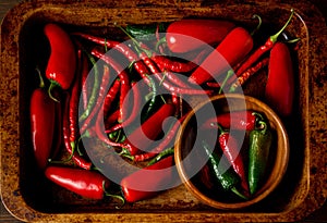 A scattering bunch of red chilies and green Romano peppers on a wooden tray. Colorful juicy hot peppers. Shot from above