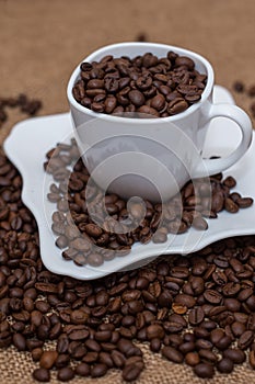 A scattering of coffee beans white cup and saucer
