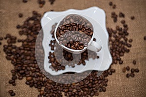 A scattering of coffee beans white cup and saucer