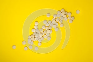 Scattering of pills on a yellow background. Natural food supplement brewer`s yeast with vitamins and microelements. Flat lay.