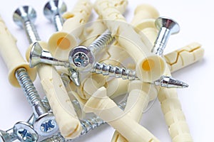 A scattering of plastic dowels with screws close-up on a white background