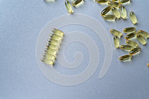 a scattering of yellow transparent fish oil capsules on a yellow background.