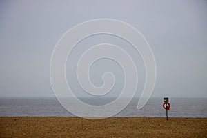 Scene at a beach with lifebuoy ring and lines of sand, sea and cloud