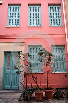 Scene of beautiful urban building facade background in pastel pink plaster paint wall, light blue entry door and window shutter