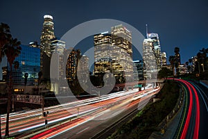 Scene of downtown Los Angeles at night, illuminated by the headlights of cars driving