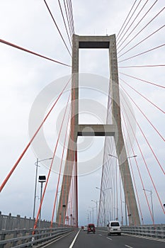 Scene of the famous Suramadu Bridge and its red suspension steel cables with cars on road
