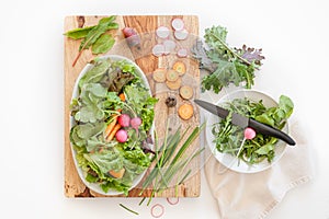A scene of fresh produce ingredients on a wooden cutting block in a kitchen.