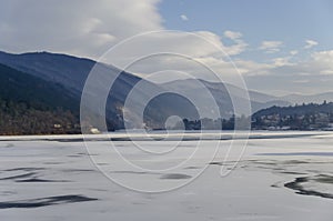 Scene with frozen lake, snowy mountain, glade, forest and residential district of bulgarian village Pancharevo, Sofia