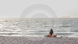 Scene with a long-haired woman meditating by the ocean on Fort Lauderdale beach, Florida, USA