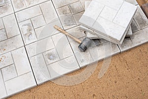 Scene of an ongoing pavement or tile installation. There is a rubber mallet and tiles on top of the partially completed pavement,