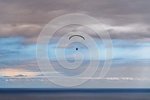 Scene of paraglider over the sea against cloudy blue sky at sunset