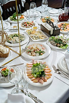 Scene of a table with appetizers. On white wooden background. Board with appetizers, meat with capers, cheese, assorted