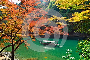 Scene with tourist boat and Hozugawa river in Arashiyama park in autumn season, Kyoto, Japan