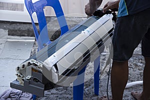 Scene of an unknown worker servicing disassemble air-conditioner parts.