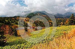 Scenery of a busdriving on a mountain highway,winding through colorful autumn forests by the mountainside in Shiga Kogen Highland