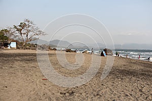 A scenery of a stretch of sand on a beach with large rocks from a distance photo