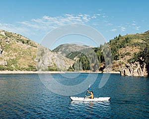 Scenery of a lonely African American girl kayaking in the lake under the mountains