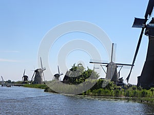 Scenery of mills near a river on a blue clear sky background