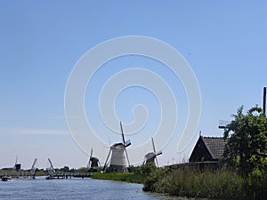 Scenery of mills near a river on a blue clear sky background