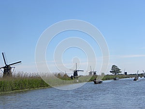 Scenery of mills near a river with lots of boats on a blue sky background