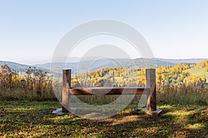 Scenery panorama in sunny day with view on mountains, green forest, meadow, blue sky and white clouds and with a bench for rest in