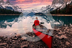 Scenery of Spirit Island with female traveler on kayak by the Maligne Lake in the sunset at Jasper national park