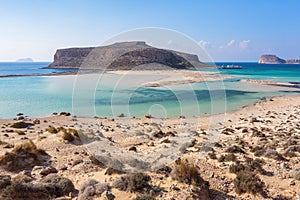 Scenery of sunny summer day with sand beach, turquoise sea and mountains. Blue horizon line. Place for tourists rest Balos lagoon.
