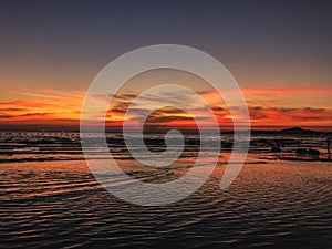 Scenery of sunset on the beach with calming waves of the ocean