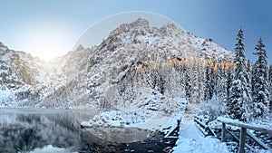 Scenery winter mountains. Amazing snowy rocks and icy lake. Beautiful view on High mountain covered by snow. Frosty nature