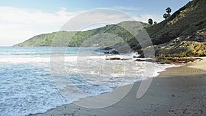 Scenery of Yanui Beach with waves and hills under blue sky at west coast.