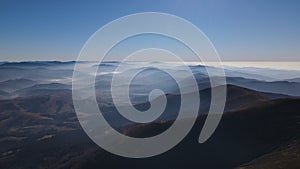 Scenic aerial view of the Carpathians in early autumn, mountain range covered with morning fog on the horizon