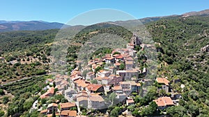 Scenic aerial view of compact village of Eus on green slopes of hill with ancient church of St. Vincent and stone castle