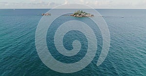 Scenic aerial view of drone flying over calm ocean with coral reef to tropical paradise island