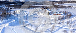 Scenic aerial view on small Tarna Vilt village in Swedish Lapland in winter cover, frosty sunny day. Roads, houses, frozen lakes,