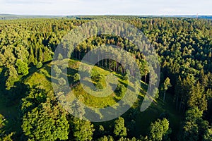 Scenic aerial view of Stirniai mound surrounded with green trees, located in Neris Regional Park near Vilnius, Lithuania, on sunny