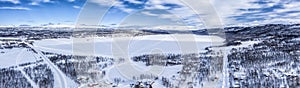 Scenic aerial view on Tarna Vilt village and Joesjo lake in Swedish Lapland in winter cover, frosty sunny day. Roads, houses,
