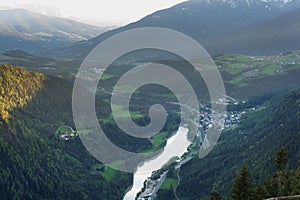 Scenic aerial view on villages in Dolomites with mountains in clouds on background and meadows on foreground