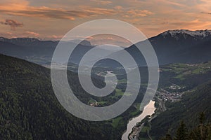 Scenic aerial view on villages in Dolomites with mountains in clouds on background and meadows on foreground