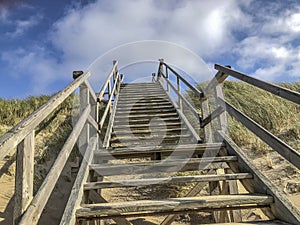 Scenic autumn sandy beach with wooden stair to climb the dam who protects Sylt from flooding