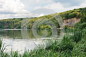 Scenic bank of river covered with lush green and yellow late summer or autumn trees.